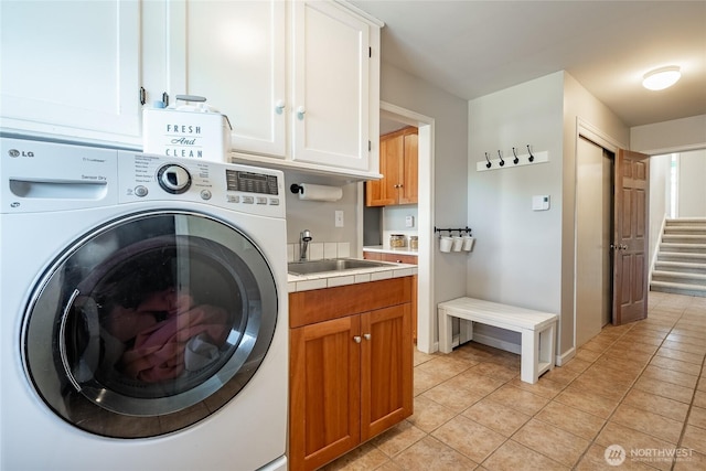 laundry room with cabinets, light tile patterned floors, washer / dryer, and sink