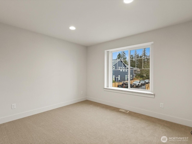 carpeted empty room featuring baseboards, visible vents, and recessed lighting