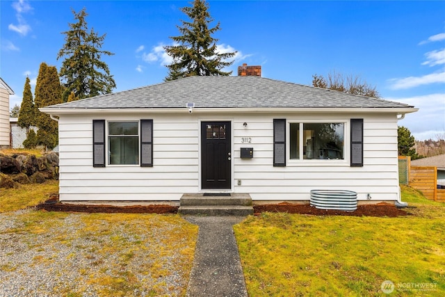 bungalow featuring roof with shingles, a front lawn, and a chimney