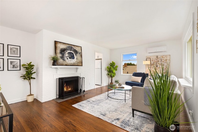 living area with a wall unit AC, a fireplace, baseboards, and dark wood-style flooring