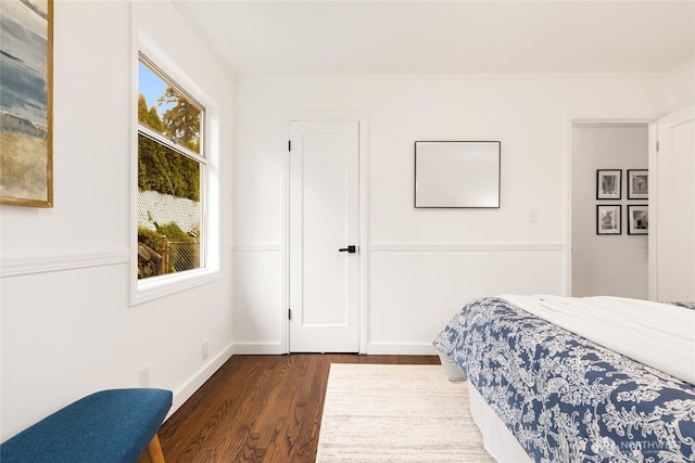 bedroom featuring dark wood-type flooring, crown molding, and baseboards