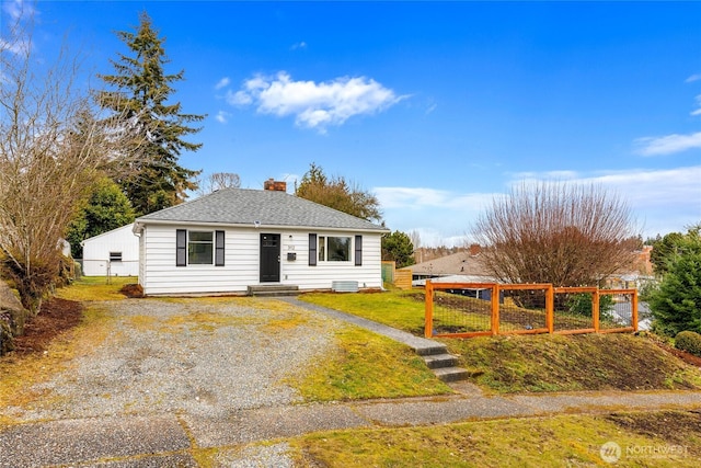 view of front of home featuring a chimney, a shingled roof, fence, driveway, and a front lawn