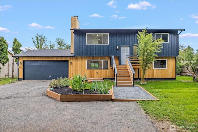 bi-level home with driveway, a garage, a chimney, stairs, and a front lawn