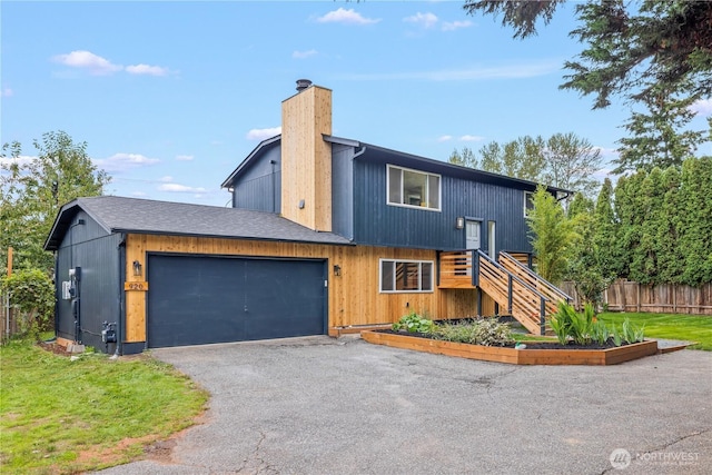 view of front of property featuring driveway, a chimney, stairway, an attached garage, and fence