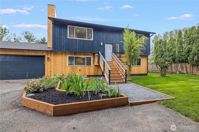 view of front of property with a garage, fence, driveway, a front lawn, and a chimney