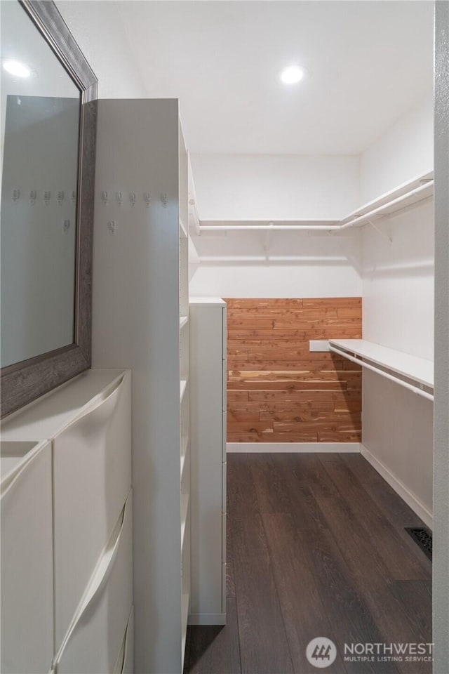 walk in closet with dark wood-type flooring