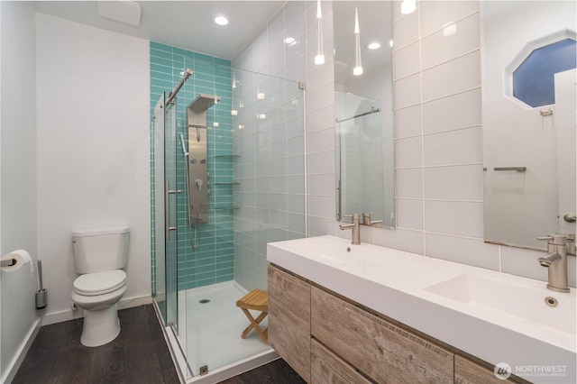 bathroom featuring hardwood / wood-style flooring, toilet, a shower with door, and vanity