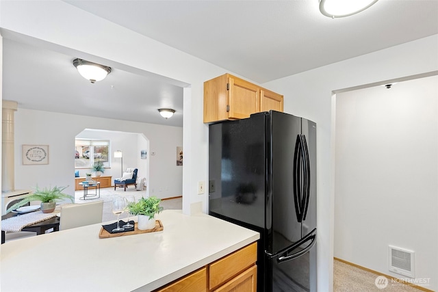 kitchen featuring black refrigerator and light carpet