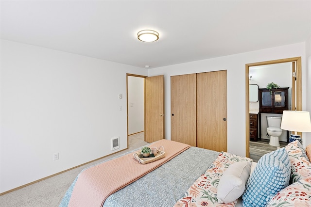 carpeted bedroom with a closet and ensuite bathroom