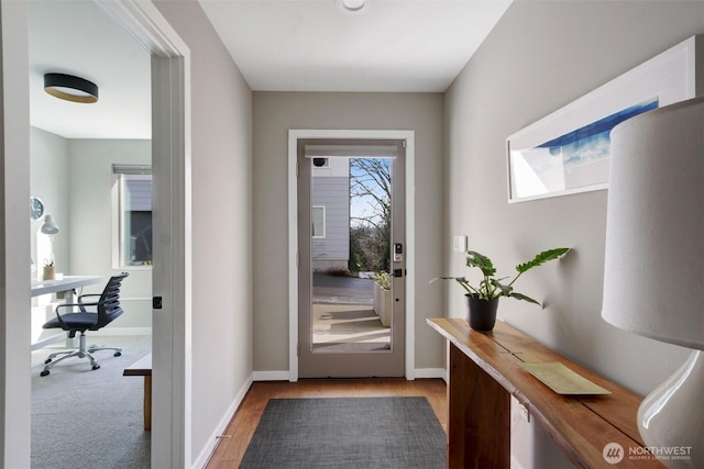 doorway featuring light wood-style flooring and baseboards