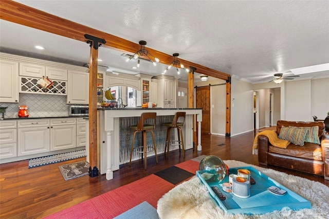 living room featuring ceiling fan, a textured ceiling, dark hardwood / wood-style flooring, and a barn door