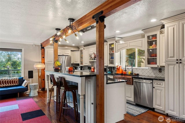 kitchen featuring hanging light fixtures, a kitchen breakfast bar, stainless steel appliances, decorative backsplash, and dark hardwood / wood-style flooring