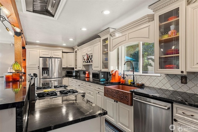 kitchen with sink, dark stone countertops, tasteful backsplash, and stainless steel appliances