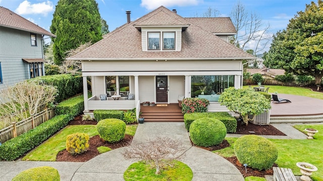 bungalow featuring a porch, a shingled roof, a front lawn, and fence