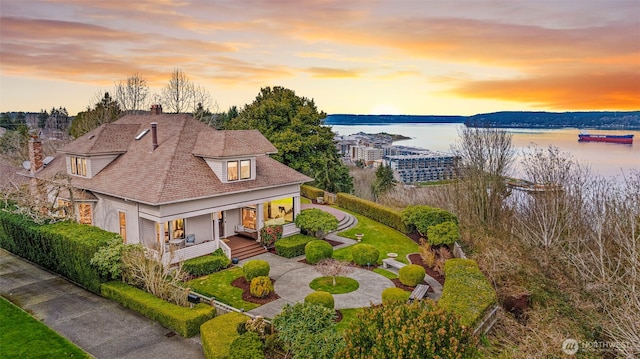 aerial view at dusk featuring a water view