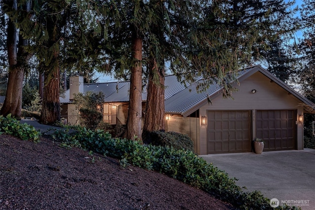 view of front of property with metal roof, driveway, a chimney, and an attached garage