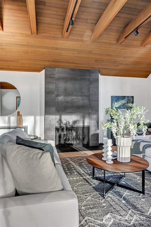 living room with a large fireplace, track lighting, lofted ceiling with beams, and wood ceiling