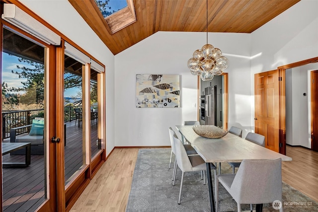 dining area featuring a chandelier, wooden ceiling, vaulted ceiling with skylight, and light hardwood / wood-style flooring