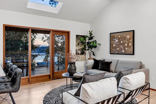 living room with light hardwood / wood-style floors and lofted ceiling with skylight