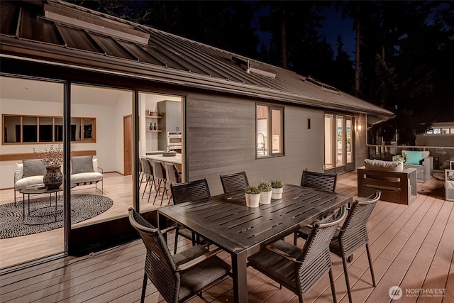 deck at twilight with outdoor lounge area and a bar