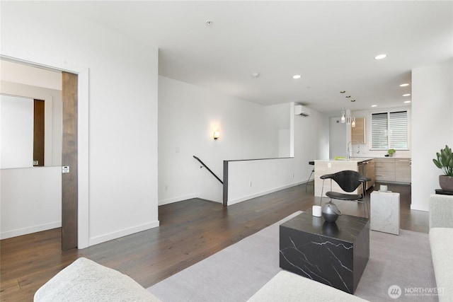 living room featuring recessed lighting, an AC wall unit, baseboards, and wood finished floors