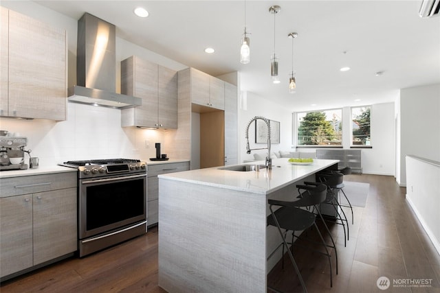 kitchen with a sink, light countertops, wall chimney range hood, backsplash, and stainless steel range with gas cooktop