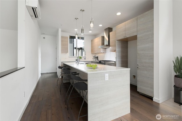 kitchen with modern cabinets, a wall mounted air conditioner, stainless steel gas range, light countertops, and wall chimney range hood