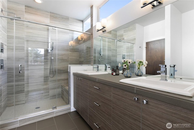 bathroom featuring tile patterned flooring, a sink, a shower stall, and double vanity