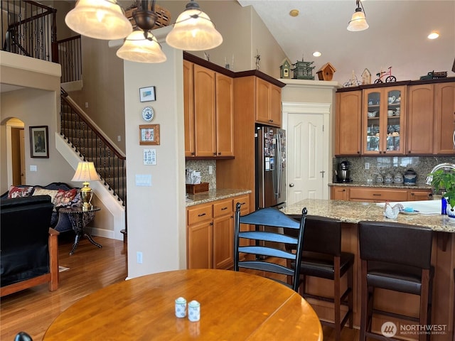 2611 Sea Crest Ave N, Long Beach, WA 98631 - kitchen featuring stainless steel fridge, glass insert cabinets, light wood-style floors, decorative backsplash, and arched walkways