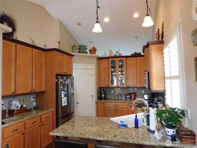 kitchen featuring appliances with stainless steel finishes, glass insert cabinets, a sink, and decorative light fixtures