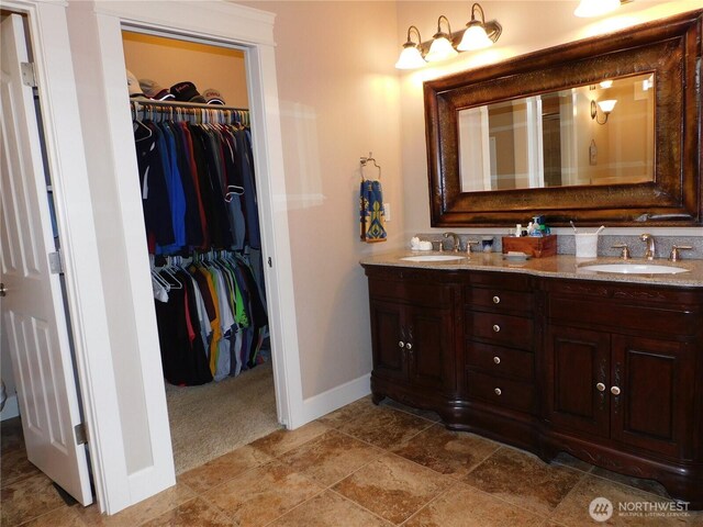 bathroom with a sink, baseboards, and double vanity