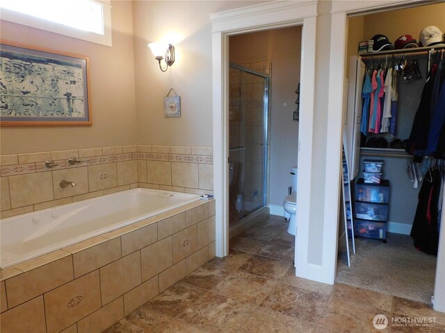 full bath with baseboards, toilet, a garden tub, a walk in closet, and a shower stall