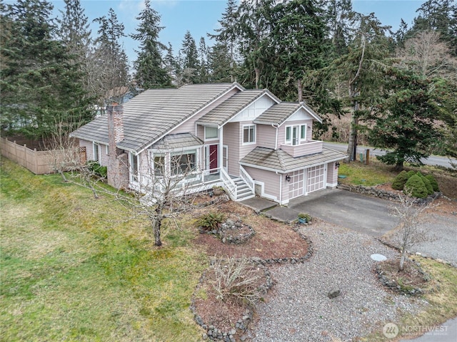 view of front of home with aphalt driveway, a garage, fence, a tiled roof, and a front yard