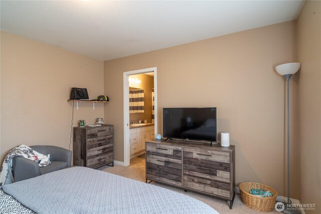 bedroom with a sink, baseboards, ensuite bath, and light colored carpet