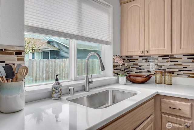 kitchen with a sink, tasteful backsplash, light countertops, and light brown cabinetry