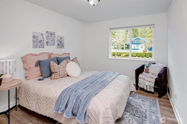 bedroom featuring baseboards, visible vents, and wood finished floors