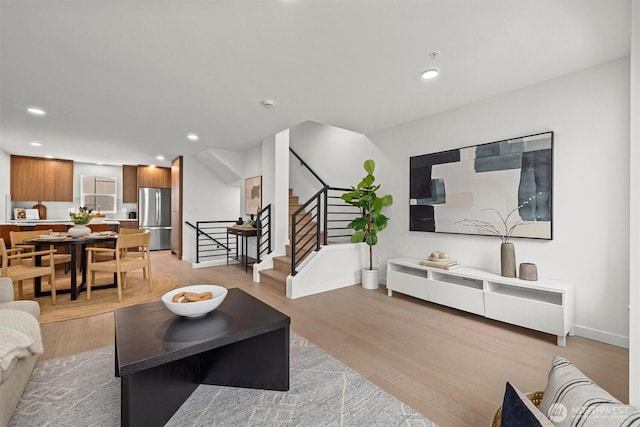 living area with stairway, recessed lighting, baseboards, and light wood-style floors