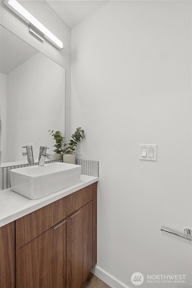 bathroom with vanity, wood finished floors, and baseboards