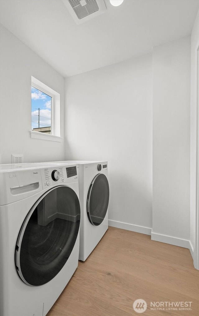 washroom with visible vents, baseboards, light wood-type flooring, laundry area, and separate washer and dryer