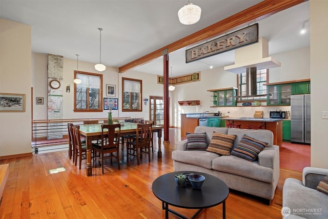 living room featuring beam ceiling, light wood-style flooring, and a toaster