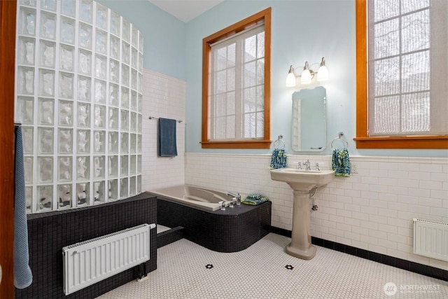 full bath with visible vents, wainscoting, radiator heating unit, tile patterned flooring, and tile walls