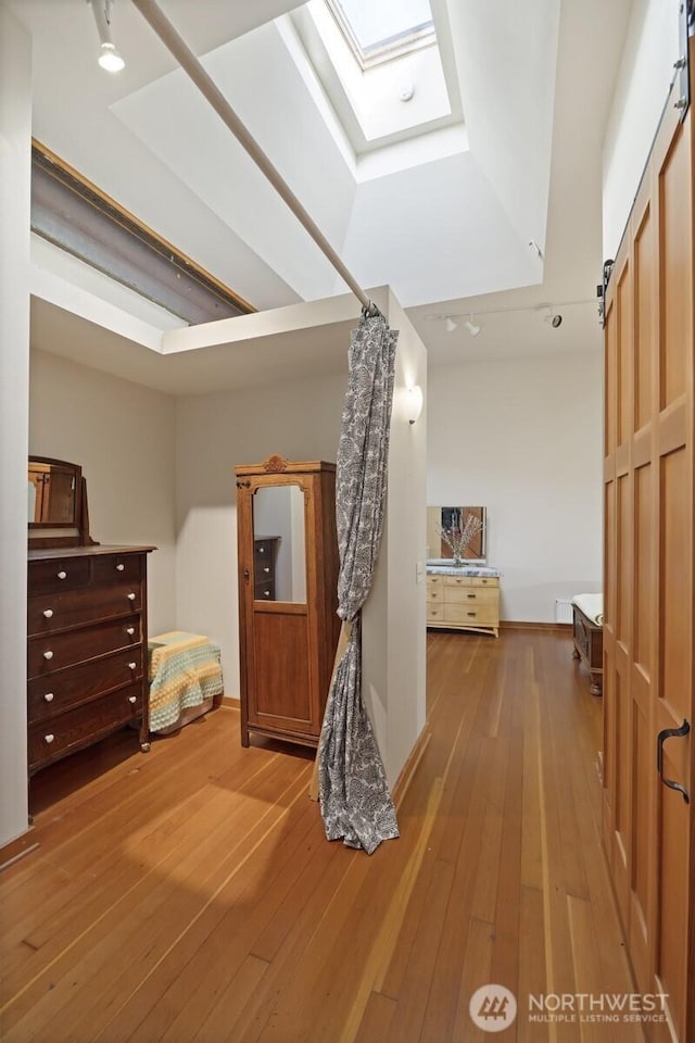 corridor with a skylight, a barn door, and wood finished floors