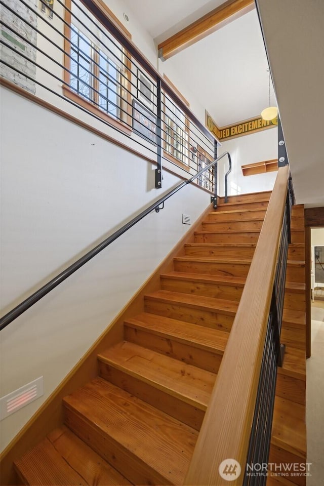 stairway featuring beam ceiling