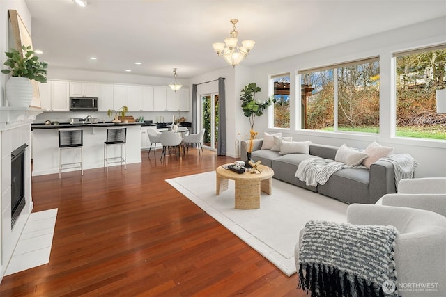 living room featuring sink, dark hardwood / wood-style flooring, a notable chandelier, and a fireplace