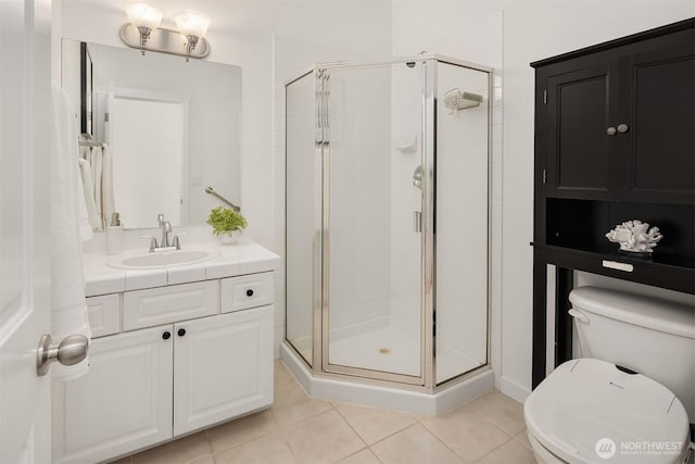 bathroom featuring tile patterned floors, toilet, vanity, and walk in shower