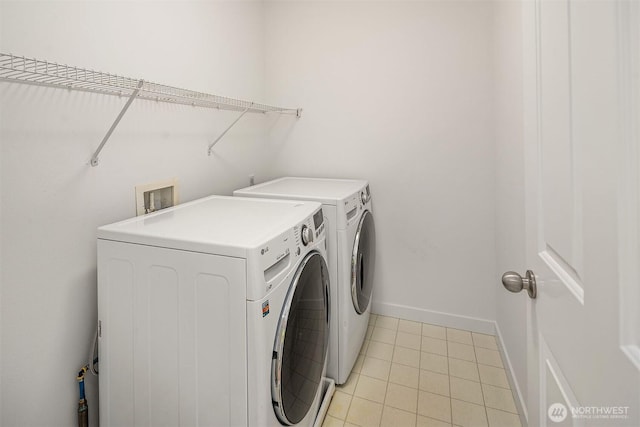 laundry area with washing machine and clothes dryer and light tile patterned floors