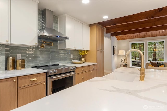 kitchen featuring a sink, stainless steel range with electric cooktop, white cabinets, wall chimney exhaust hood, and brown cabinetry