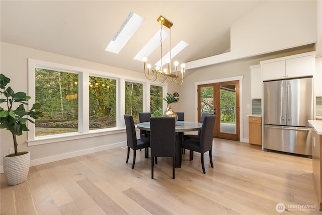 dining room with light wood finished floors, baseboards, high vaulted ceiling, french doors, and a chandelier