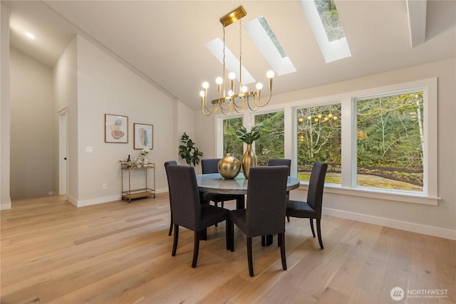 dining area with baseboards, high vaulted ceiling, light wood-type flooring, and an inviting chandelier