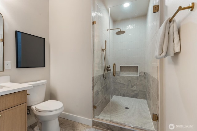 bathroom with marble finish floor, toilet, a stall shower, vanity, and baseboards